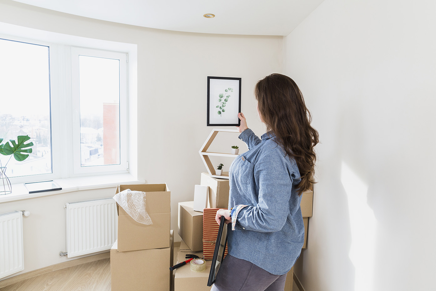 Primer plano de una joven sosteniendo hojas enmarcando la foto de su nuevo hogar